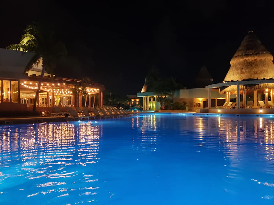 picture of a pool at night with restaurants on the side
