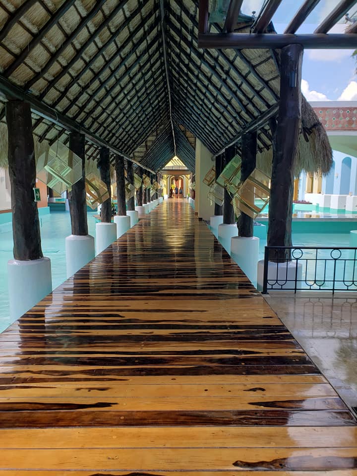 picture of a covered, wooden walkway through water at a hotel