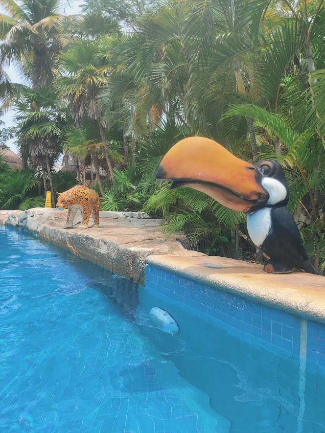 picture of a toucan statue and a tiger statues by a lazy river