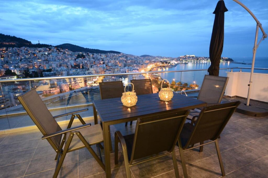 picture of a table with lanterns overlooking the sea and a town