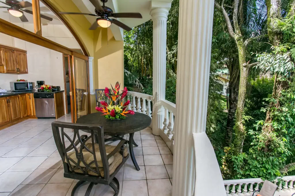 picture of a balcony, with a table, two chairs and flowers