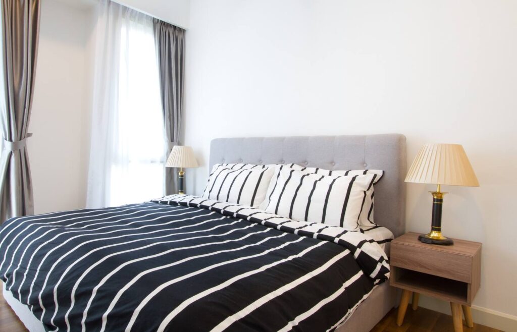 picture of a bed with black and white stripped bedsheets