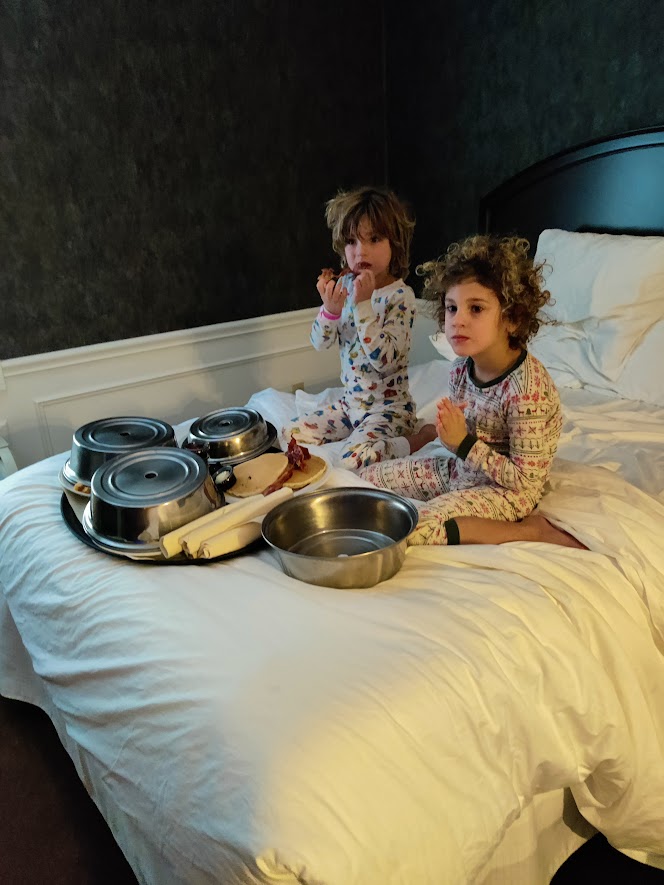 picture of two children eating on a bed