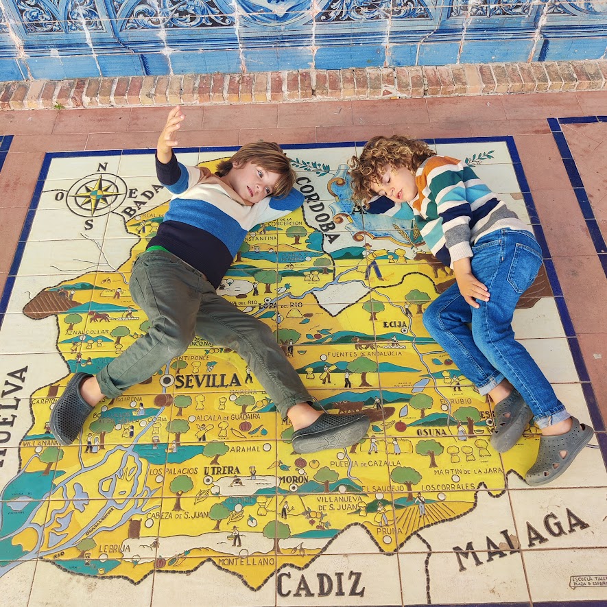 picture of two children laying down on a mural with the map of Spain on it