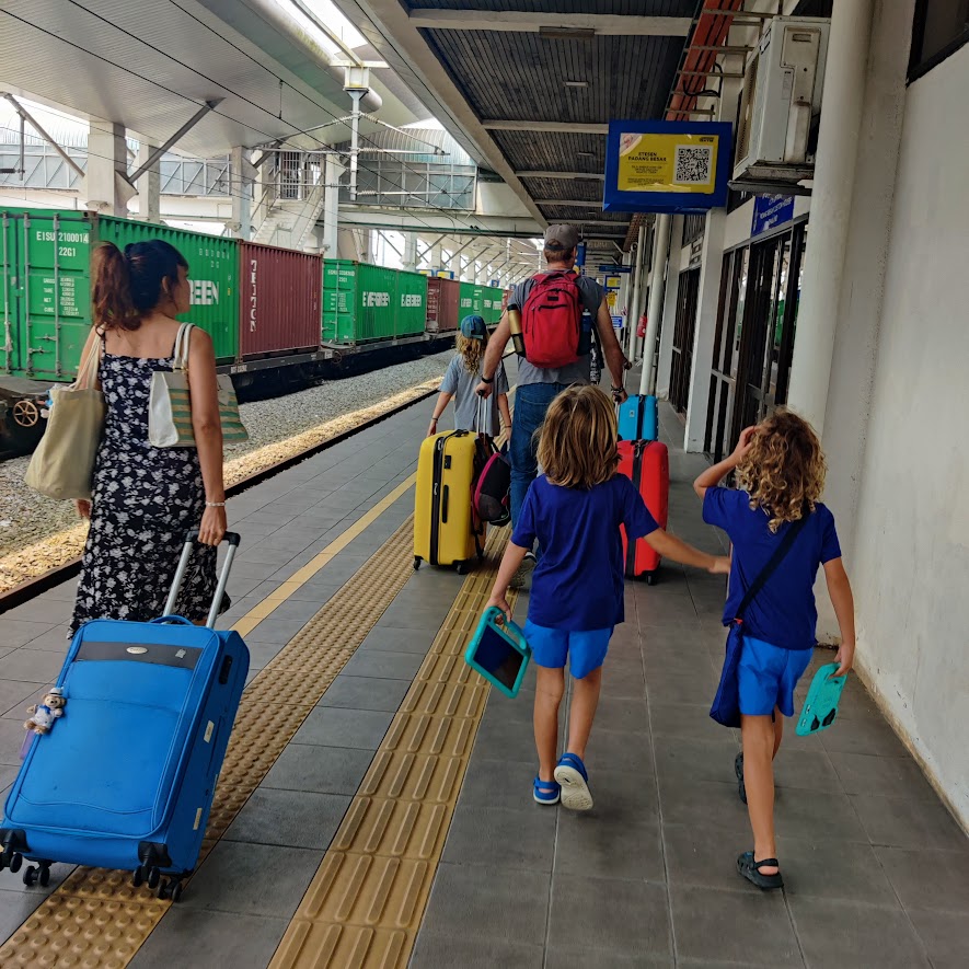 picture of two kids and two adults pulling their luggage at a train station