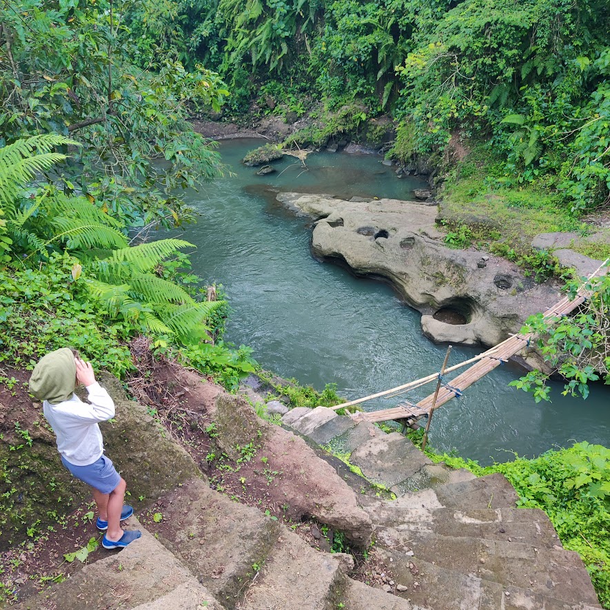 picture of a child by a hanging bridge over a river