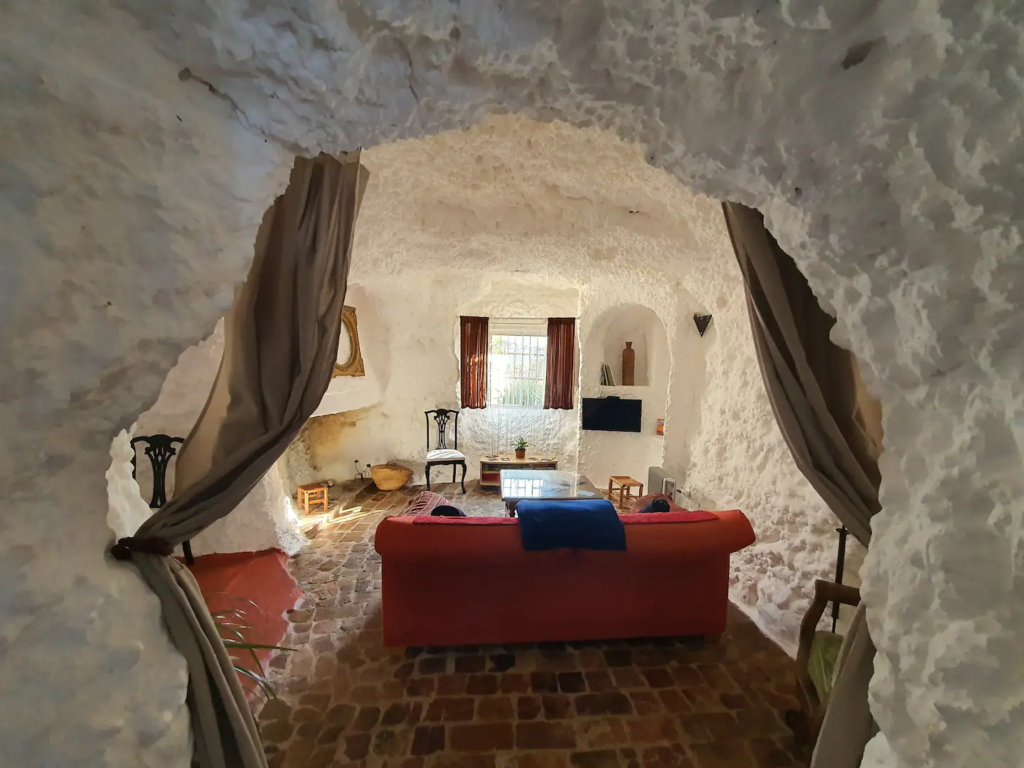 picture of the inside of a cave house - a red couch and a window