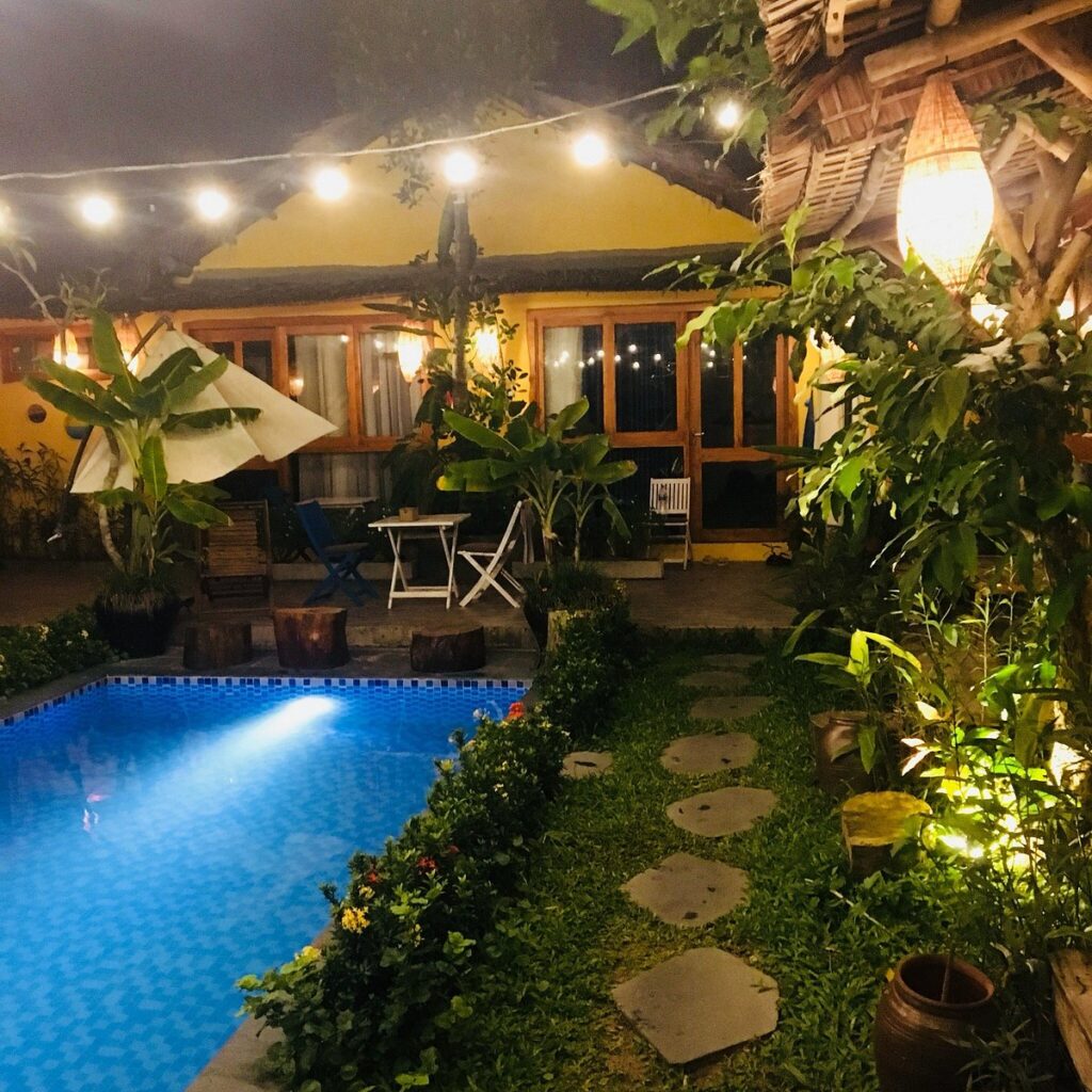 picture of a pool at night, in a lush hotel court yard